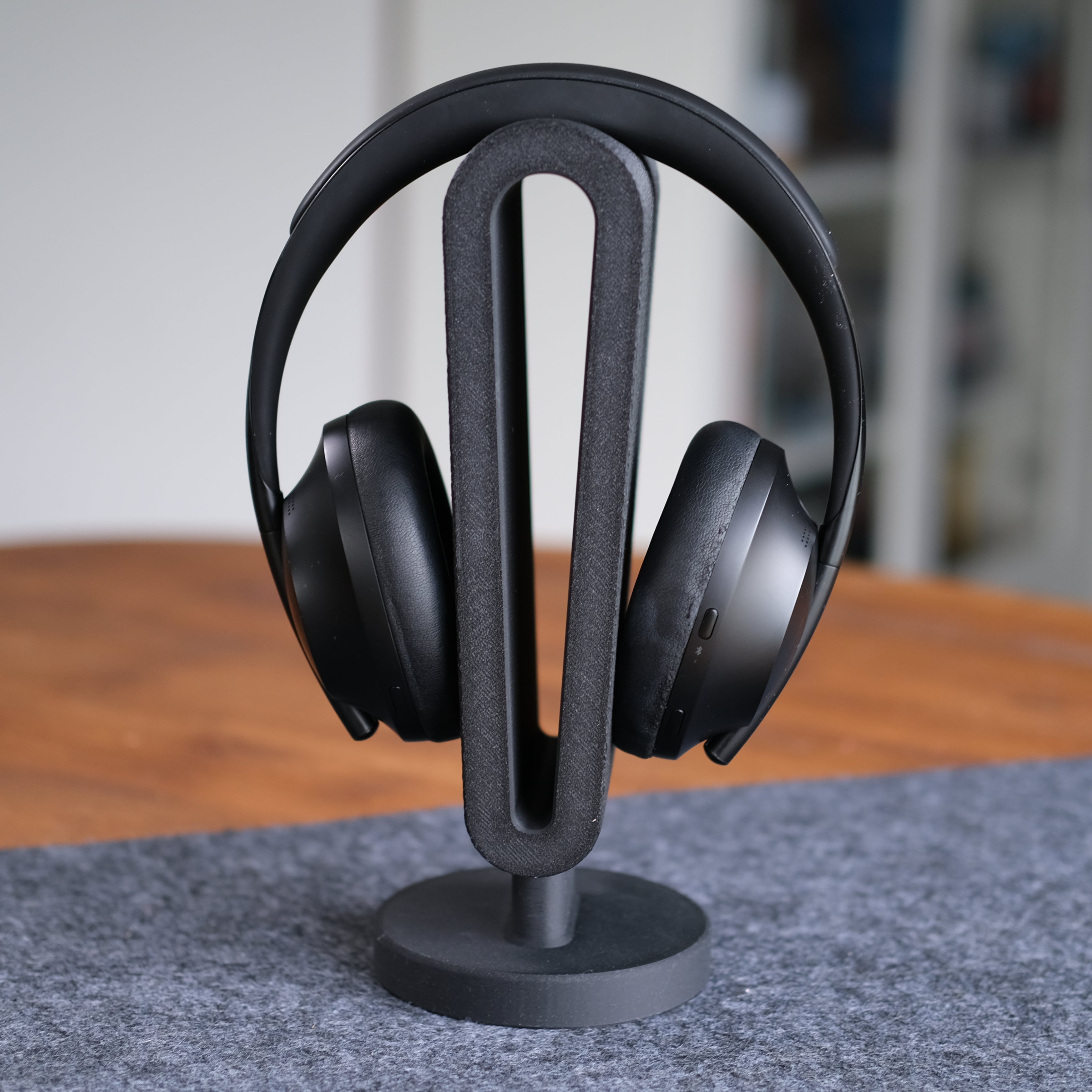 Headphone Display Stand holding a pair of black headphones, showcasing functionality and style on a wooden desk.