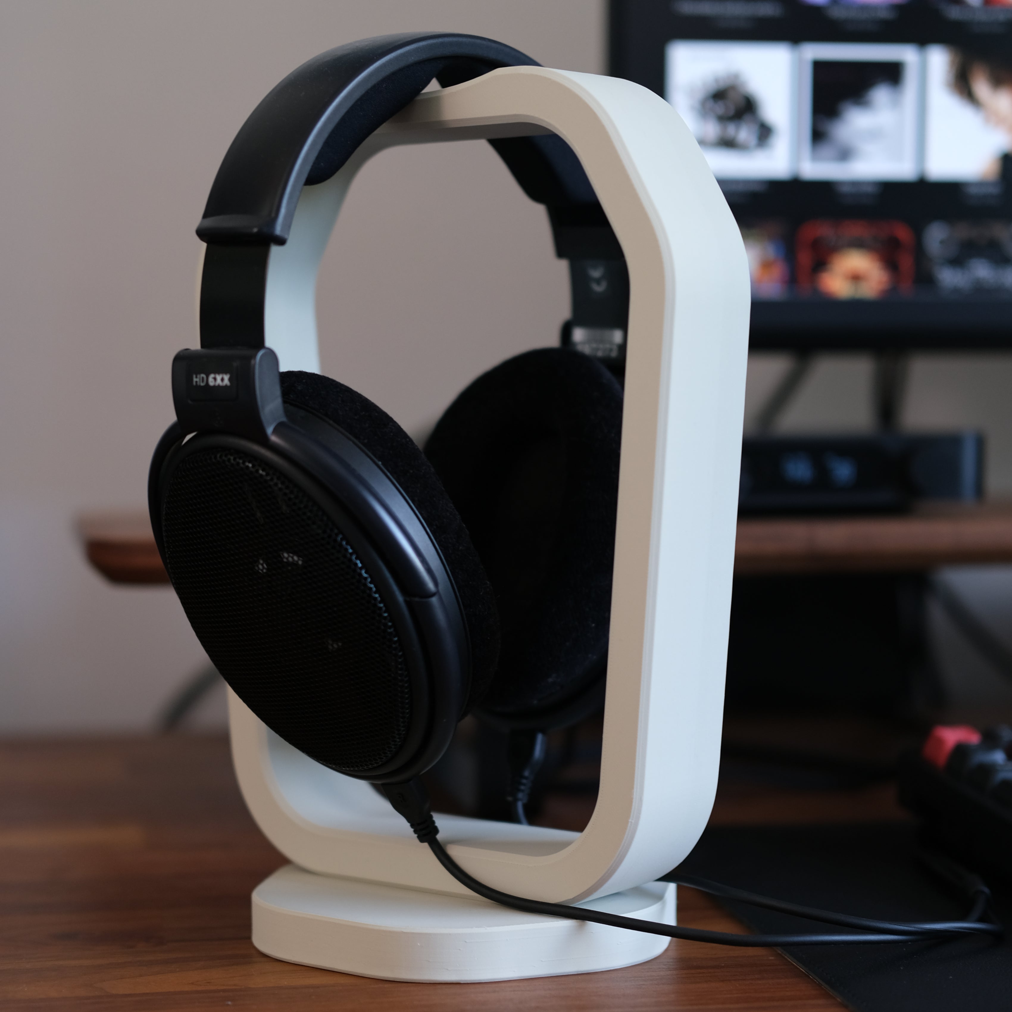 Headphone Display Stand holding a pair of black headphones, showcasing functionality and style on a wooden desk.