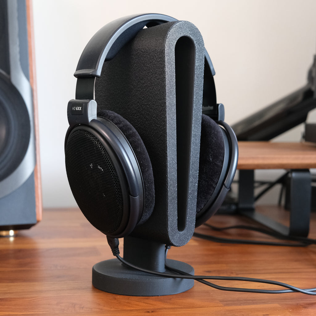 Headphone Display Stand holding a pair of black headphones, showcasing functionality and style on a wooden desk.