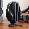 Headphone Display Stand holding a pair of black headphones, showcasing functionality and style on a wooden desk.